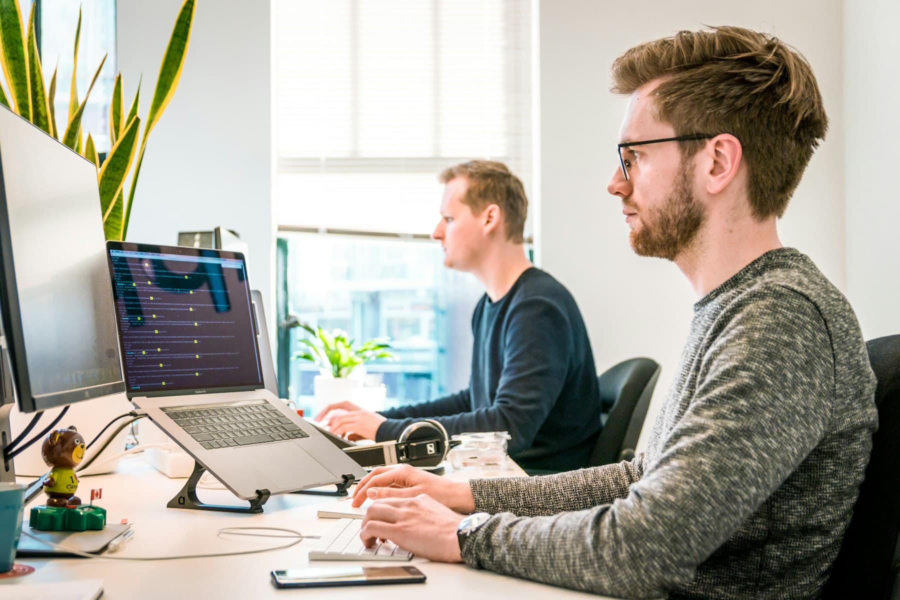 Two software engineers working at monitors, running a project through the agent development life cycle (ADLC)
