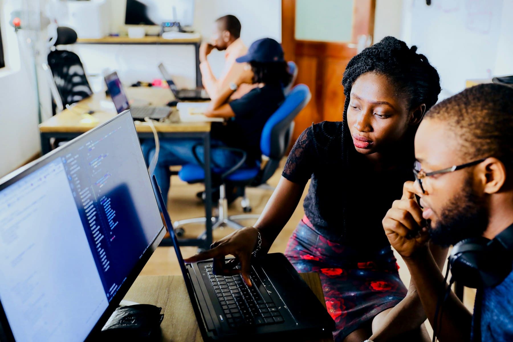 Two learners reviewing code together on a laptop, as an Agentic AI Engineer cohort team does