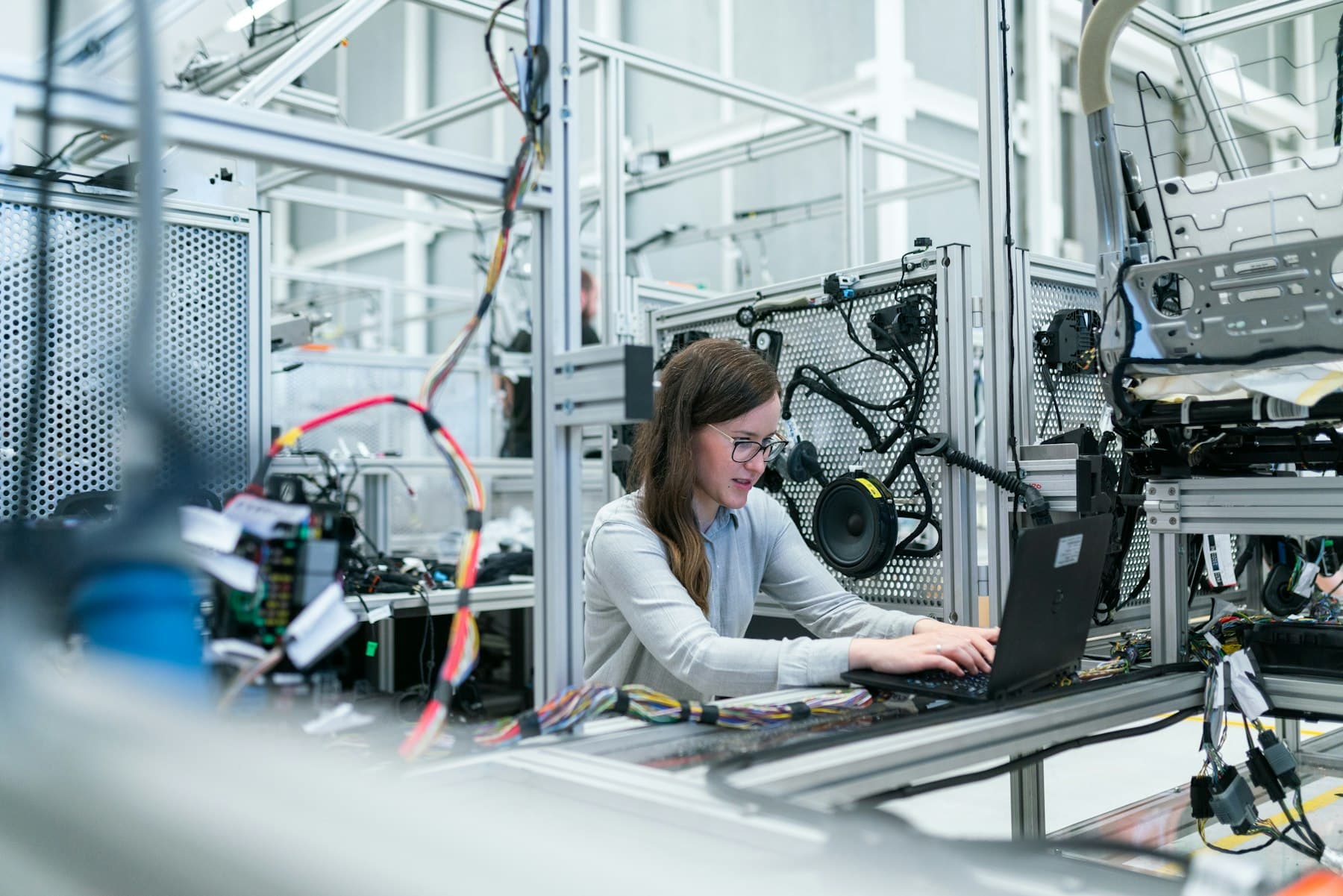 Engineer working on a laptop inside a robotics workcell, the kind of room campus AI lab software runs in